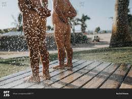 Naked toddler boys rinsing off at beach shower stock photo - OFFSET