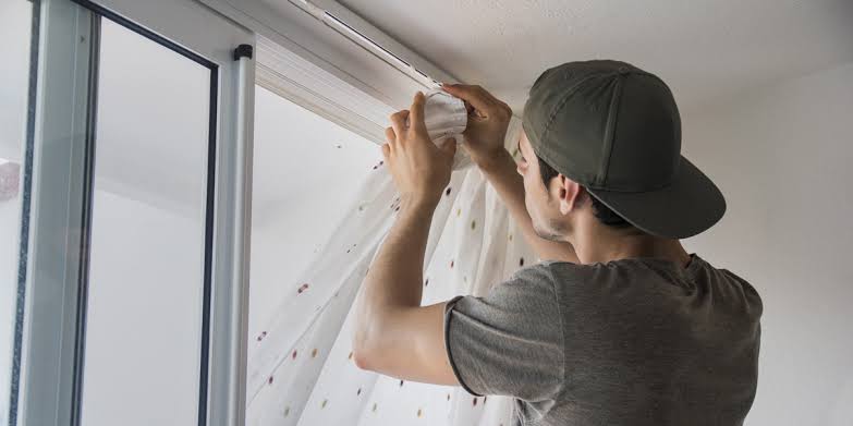 Lewisham fitter measuring a window before curtain pole fitting