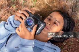 Lifestyle Young Latina Lying On The Floor Taking Pictures With Analog  Camera Stock Photo