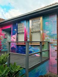 Vibrant Abstract Mural Painted On The Exterior Of A House The Colors Contrast With The Traditional Archi Wall Paint Designs House Design Brick Wall Background