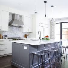 Although the contrast is subtle, it's just enough to anchor this airy kitchen. Gray Center Island With Vapor Counter Stools Transitional Kitchen