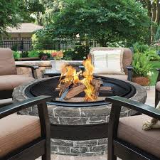Patio with fireplace of a modern villa surrounded by green nature. Home Garden Patio Fire Pit Bowl Outdoor Fireplace Stone Round Heater Wood Burning Backyard Yard Garden Outdoor Living