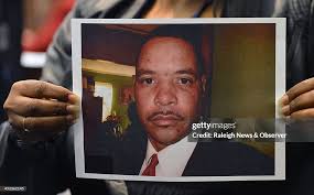 The Clerk of the Court holds up a photo of Reginald Daye, 46. that... News  Photo