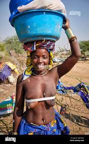 Portrait of a Mucubal woman with the traditional rope tying her breasts  carrying a load of clothes for washing Stock Photo - Alamy