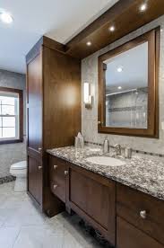 Weve a white small bathroom with dark brown high cabinet, mirror cabinet and wall tiles, grey floor tiles bathroom white vessel shape free standimg bathtub undermount sink frameless wall mirror dark gray tile walls. Bathroom Remodel Dark Brown Cabinets Custom Soffit With Built In Lights Framed Mirror To Ma Bathrooms Remodel Bathroom Remodel Master Small Bathroom Remodel