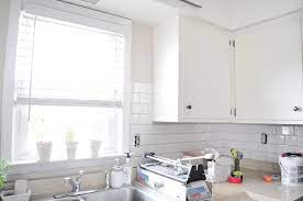 The shiny offset subway tiles in this glossy kitchen contrast beautifully with the wood countertops, and the backsplash appears clean and glossy as tiles travel up the wall and around high windows. Subway Tile Backsplash