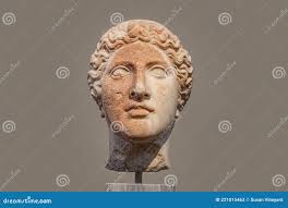 Damaged Head of Ancient Greek Statue with Part of Face Rough and Orange  from Deterioration Isolated Against Tan Background Stock Photo