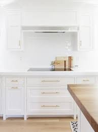 white kitchen cabinets with long brass