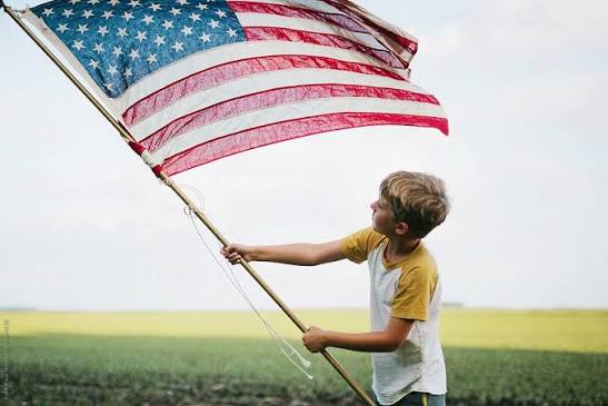 Boy Waving A Large American Flag" by Stocksy Contributor "Kelly Knox" - Stocksy
