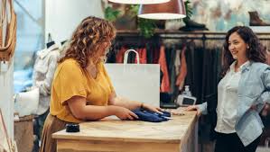 Selling products, processing returns, accepting payments is a retail clerk a cashier? Shop Clerk Assisting Customer At Clothing Store Checkout Jacob Lund Photography Store Premium Stock Photo