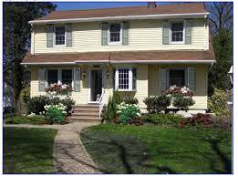 Flowers, bushes and other landscape surround the house. Pin By Ann Marie Herrera On Home Exterior Exterior Paint Colors For House Brown Roof Green Shutters