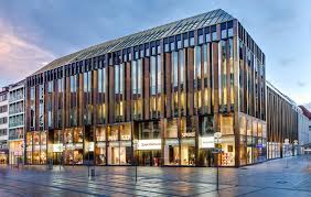 Zur neuhauser straße ist das gebäude auf voller höhe mit einer fassade aus glas und messing verkleidet. Fkn Gruppe Joseph Pschorr Haus Munchen