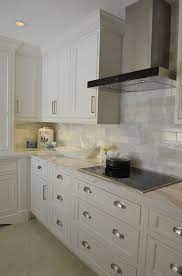Black worktop, range hood, and refrigerator meet the white units in stunning contrast. White Kitchen With Driftwood Peninsula Koby Kepert Kitchen Remodel Countertops Kitchen Design Rustic Kitchen