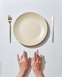 The charger plate rests under another food. Waiting For Dinner At The Table Empty Plate And Hands By Yaroslav Danylchenko