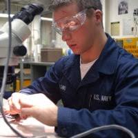 Electrician's Mate 2nd Class Bruce A. Bunnell strips the ends of  newly-wound copper wires to make the necessary connections in a high  pressure air compressor (H-PAC) motor being rebuilt aboard the USS