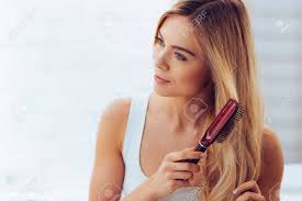 The appropriate brush for someone with long, curly hair will be drastically different than the best brush for fine or thinning hair. Combing Her Hair To Keep It Healthy Close Up Of Beautiful Young Woman Brushing Her Long Hair And Looking Away While Standing Against White Brick Wall Stock Photo Picture And Royalty Free Image