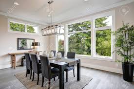 This chandelier can be hung or attached. Luxurious Modern Dining Room Boasts A Black Dining Table Illuminated By A Rectangular Chandelier And Surrounded By Gray Velvet Dining Chairs Over Taupe Sisal Rug Finished With Rustic Console Table Stock Photo