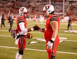 two utah football players share a handshake prior to the