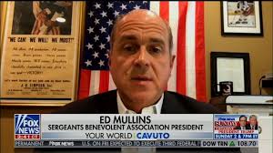 Head of NYPD union gives Fox News interview with QAnon mug in background
