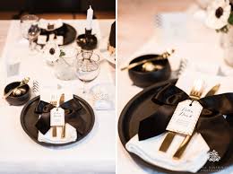 Top view of plates and silverware arranged with wineglasses and flowers on table. Trendy Black White And Gold Wedding Stationery Wedding Cake And Table Decor By Nina Hintringer Photography