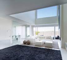 The walls are white for an airy look and the floors are concrete. Interior Of Modern Living Room With Soft Simple Furniture And High Ceiling Stockphoto
