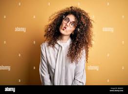 Young beautiful brunette woman with curly hair and piercing wearing shirt  and glasses making fish face with lips, crazy and comical gesture. Funny  exp Stock Photo - Alamy