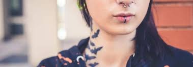 Portrait of a smiling woman with piercings and tattoos, on a white background. 27 Creative Tattoo And Piercing Combinations