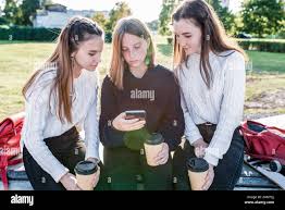 Tres Ninas Alumnas Adolescentes De 12 14 Anos De Edad Dia De Otono Ciudad Veraniega Ver Videos Smartphone La Aplicacion En Linea De Las Redes Sociales En Internet Caliente Fotografia De Stock Alamy
