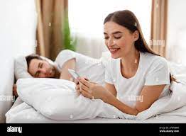 Cheating Wife Texting On Phone While Husband Sleeping In Bedroom Stock  Photo - Alamy