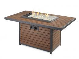 A gas fire pit table, in the simplest terms, is a portable propane gas tank connected to a burner in a concave bowl or basket in the middle of a very stylish table meant to provide warmth in your patio or backyard. Kenwood Rectangular Chat Height Gas Fire Pit Table The Outdoor Greatroom Company