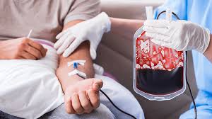 Healthcare worker holding a blood bag while a patient receives a transfusion via IV in the arm