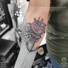 This tattoo shows the image of a rose right at the mouth of an old skull. Tattoology Studio Anchor Compass And Wheel With Clock Tattoo