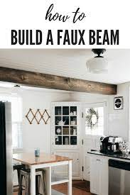 White kitchen with dark wood beams and wall shelves kitchen. How To Plank A Ceiling Build A Faux Beam Showit Blog Kitchen Remodel Faux Beams Farmhouse Style Kitchen