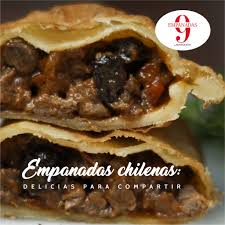 Empanadas chilenas tradicionales típicos con carne, cebolla, huevos y aceitunas en la tabla de cortar rústica mapuche en el fondo de madera azul. Que Tiene La Empanada Chilena Que La Novecento Asuncion Facebook