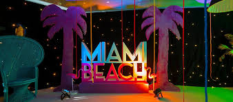 Miami Beach Theme Event With Peacock Chair Photo Op Giant Letter Sign Glitter Palms And Star Cloth Wall Beach Themed Party Miami Vice Party Miami Party