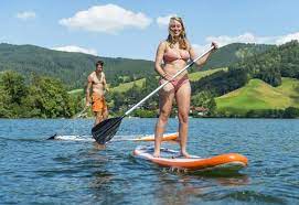 Junger Mann und junge Frau auf einem Stehpaddel Board, Stand-Up-Paddel oder SUP  auf einem See, Schli