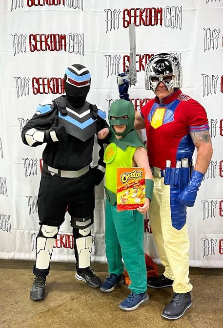 Judomaster cosplayer alongside Peacemaker and Vigilante at a convention fan meetup, AI generated