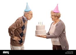 Ältere Frau mit einer Geburtstagstorte mit Kerzen und ein älterer Mann bläst  sie isoliert auf weißem Hintergrund Stockfotografie - Alamy