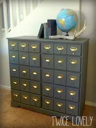 The addition of faux drawer fronts, shiny brass labeled cup pulls, and wheels, it now looks like a card catalog and functions as a desk. Faux Card Catalog At Twice Lovely Card Catalog Card Catalog Cabinet Library Card Catalog