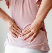 Woman with lower pain back on white background. 8 Causes Of Lower Back Pain In Women According To Doctors