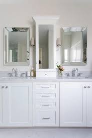 A beveled medicine cabinet is a medicine cabinet that features bevel detailing. Beveled Vanity Mirrors Are Hung Flanking A Glass Front White Medicine Cabinet Lit By Nickel Sc Bathroom Vanity Bathroom Vanity Makeover Small Bathroom Vanities