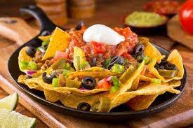 A Plate Of Delicious Tortilla Nachos With Melted Cheese Sauce Ground Beef Jalapeno Peppers Red Onion Green Onions Tomat Tortilla Nachos National Nacho Day Food