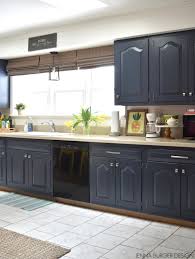 Blue bar cabinets accented with brass pulls are fitted with a white and gray marble countertop mounted against a white and gray marble slab backsplash and glossy blue glazed picket tiles styled with white shaker cabinets and wood hardware finished with a light white quartz countertop in a transitional. Kitchen Cabinet Makeover Reveal