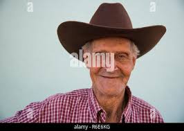 Older man in a cowboy hat with a gray beard holding a lever action rifle  with a black background, Vertical Stock Photo