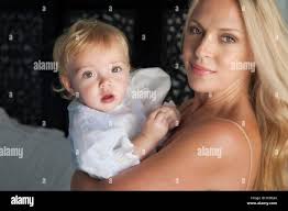 Mom holds her one-year-old baby by the hand for a walk in the park by the  river Stock Photo