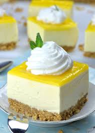 Piece Of No Bake Lemon Cheesecake Bar On A White Plate With Cool Whip Topping In Front Of Couple Of P Cheesecake No Bake Lemon Cheesecake Lemon Cheesecake Bars