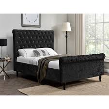 Black velvet curtains hang from a window located behind a capiz nightstand placed over a black velvet trunk and beside a moroccan style bed dressed in yellow and orange bedding. Dione Bed Frame Crushed Velvet Double King Super King Fads