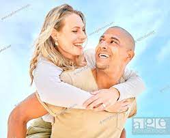 Happy interracial couple enjoying a piggyback ride outside against a blue  sky having fun and smiling..., Stock Photo, Picture And Low Budget Royalty  Free Image. Pic. ESY-063458526 | agefotostock