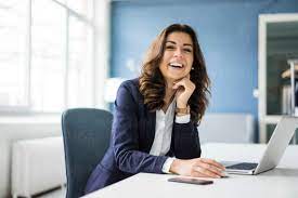 Portrait of laughing businesswoman sitting at desk in the office -  MOEF00457 - Robijn Page/Westend61
