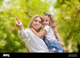 Happy Mom Showing Daughter Something Pointing Finger Standing In Park Stock  Photo - Alamy